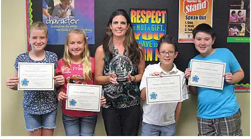 Four kids holding awards and smiling.