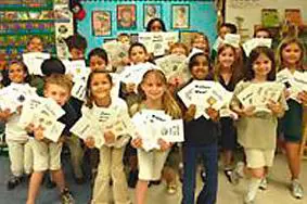 A group of children holding up white paper.