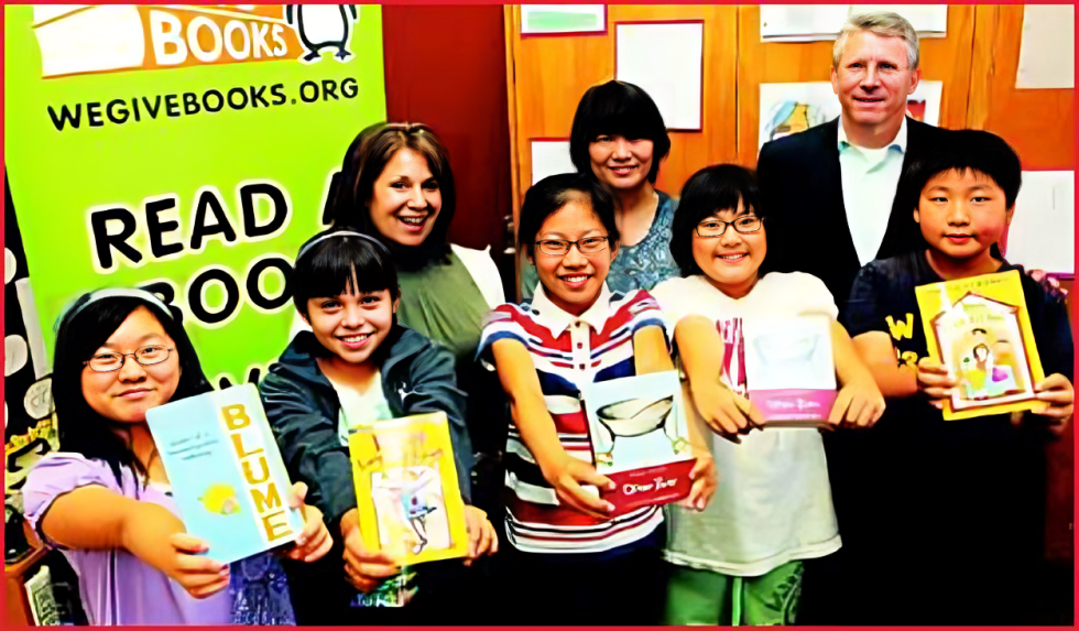 A group of people holding books in front of a sign.