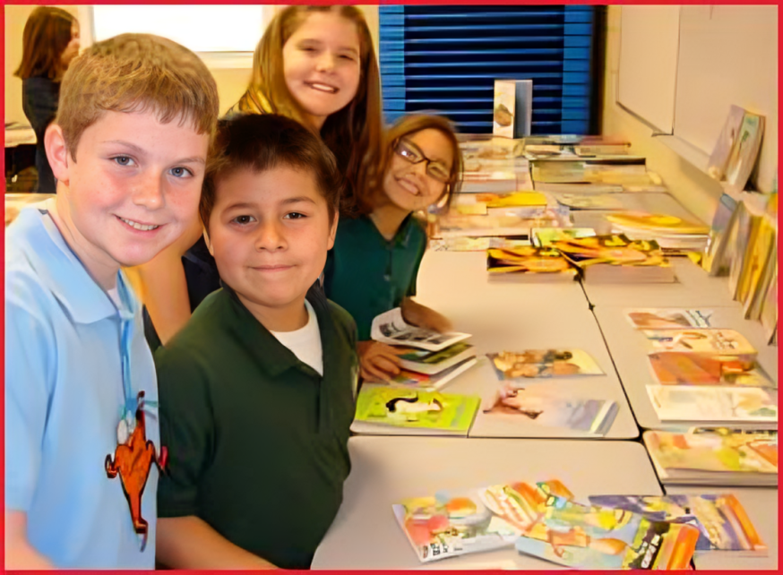 A group of children sitting at a table with books.