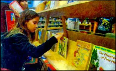 A girl is looking at books in the library.