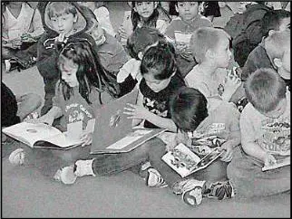 A group of children sitting on the ground reading books.