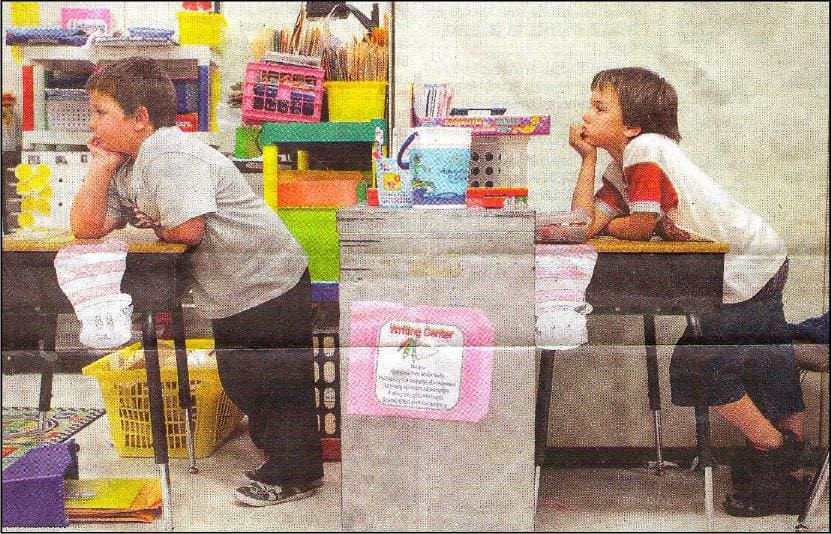 A child sitting at a table with another child.