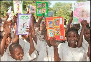 A group of children holding up books and smiling.