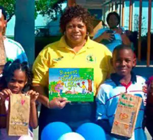 A woman holding a book with children in front of it.